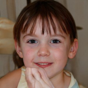 A young girl looks directly at the camera, smiling. A fleshy appendage is close to her chin.